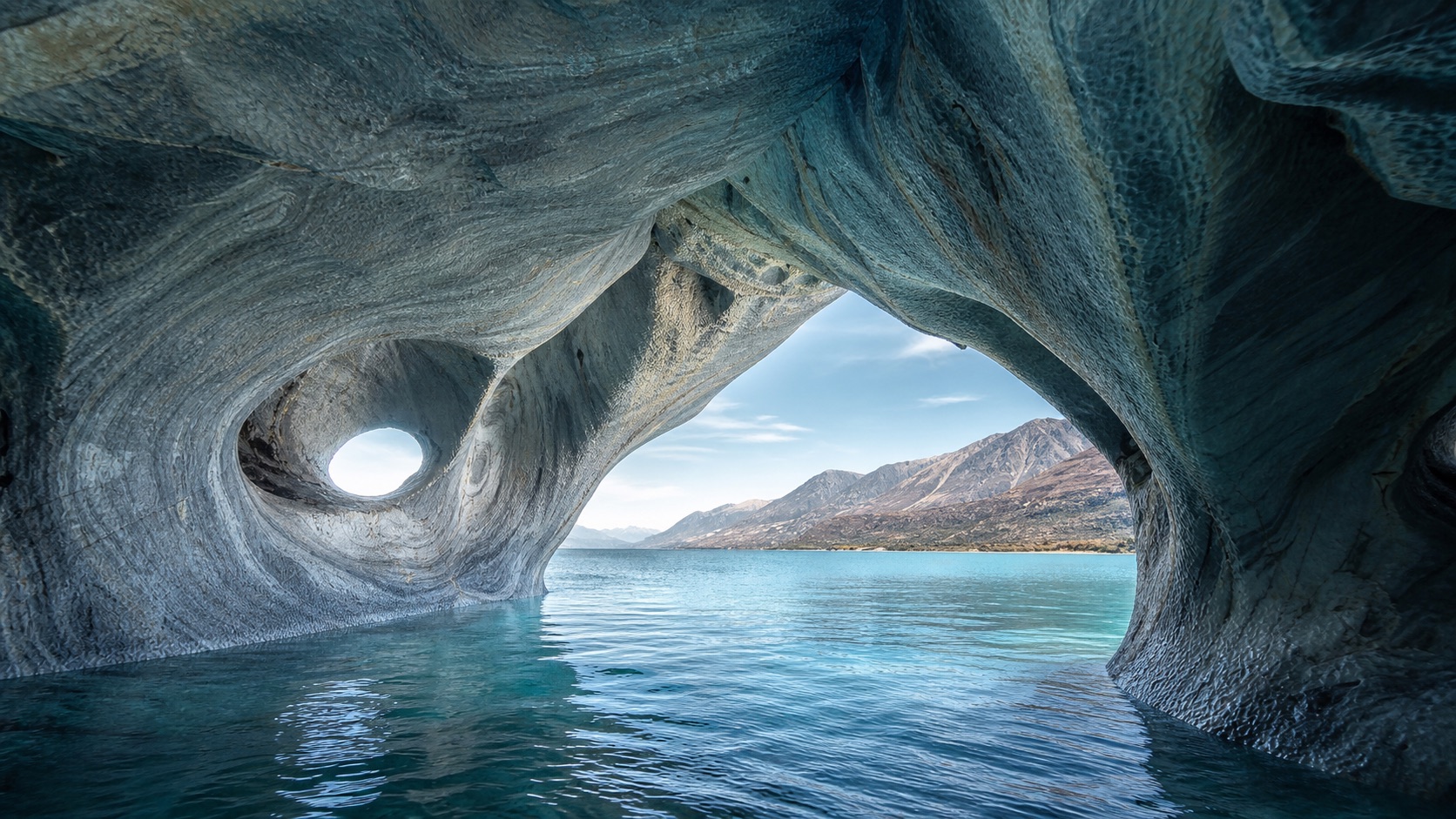 Interior de una caverna de mármol abierto hacia las aguas turquesa del lago General Carrera