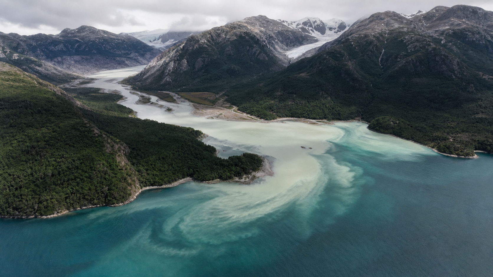 Río de deshielo mezclándose con un fiordo patagónico
